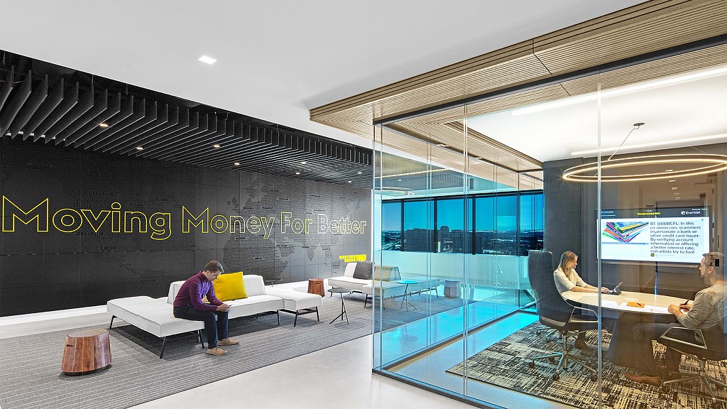 A group of people sitting in a room with a large screen.